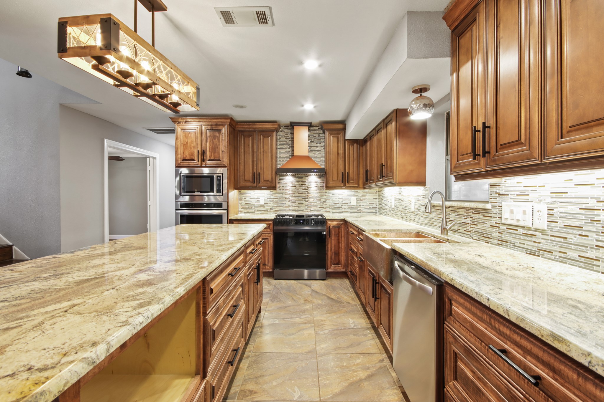 35 Susan Drive Cleveland, TX 77327 - Photo 8 of 33 This kitchen features elegant wooden cabinetry, granite countertops, and stainless steel appliances, including a double oven and dishwasher. A stylish tile backsplash and modern pendant lighting add a touch of sophistication.