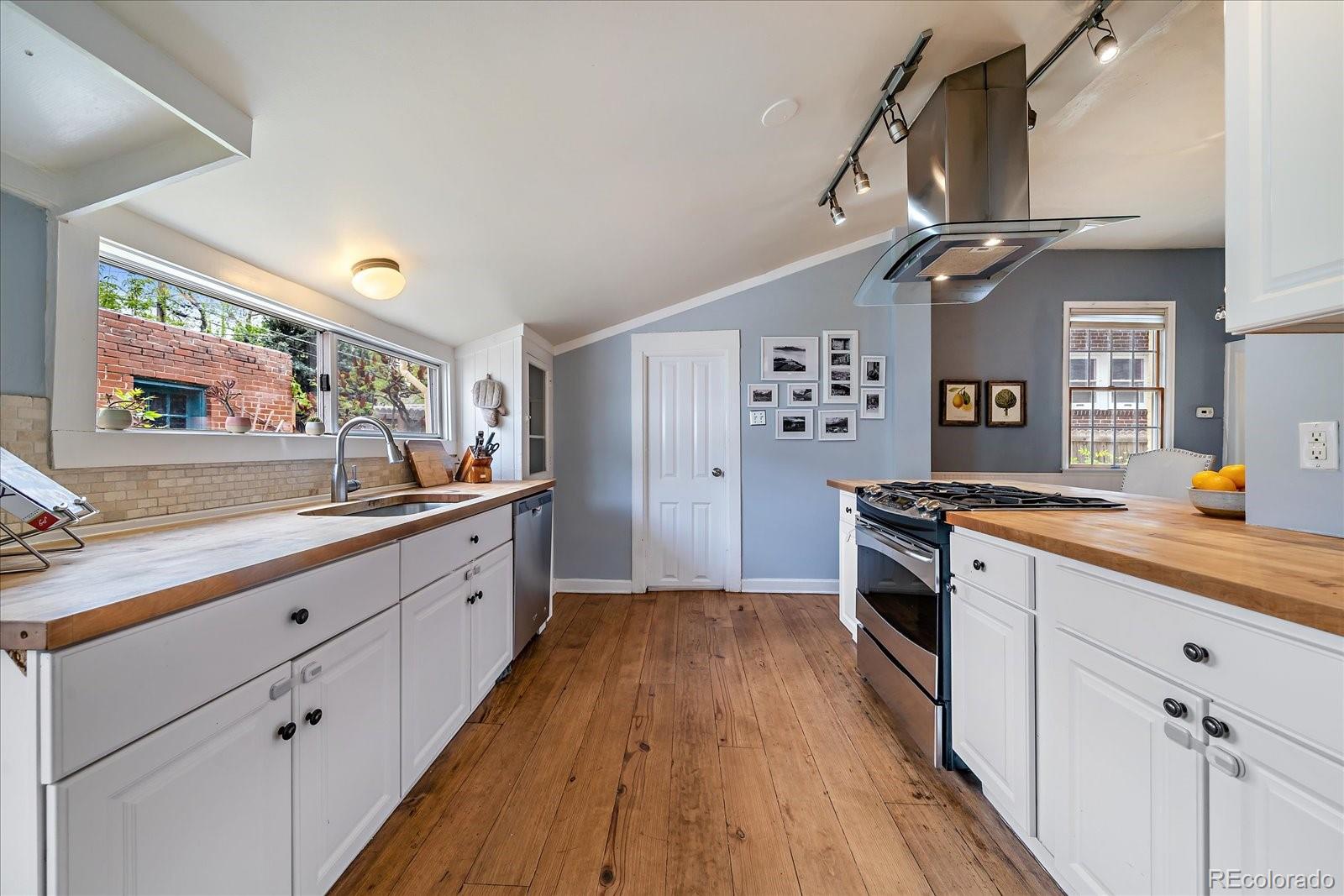 1776 South Logan Street Denver, CO 80210 - Photo 12 of 21 a large kitchen with cabinets a sink a window and stainless steel appliances
