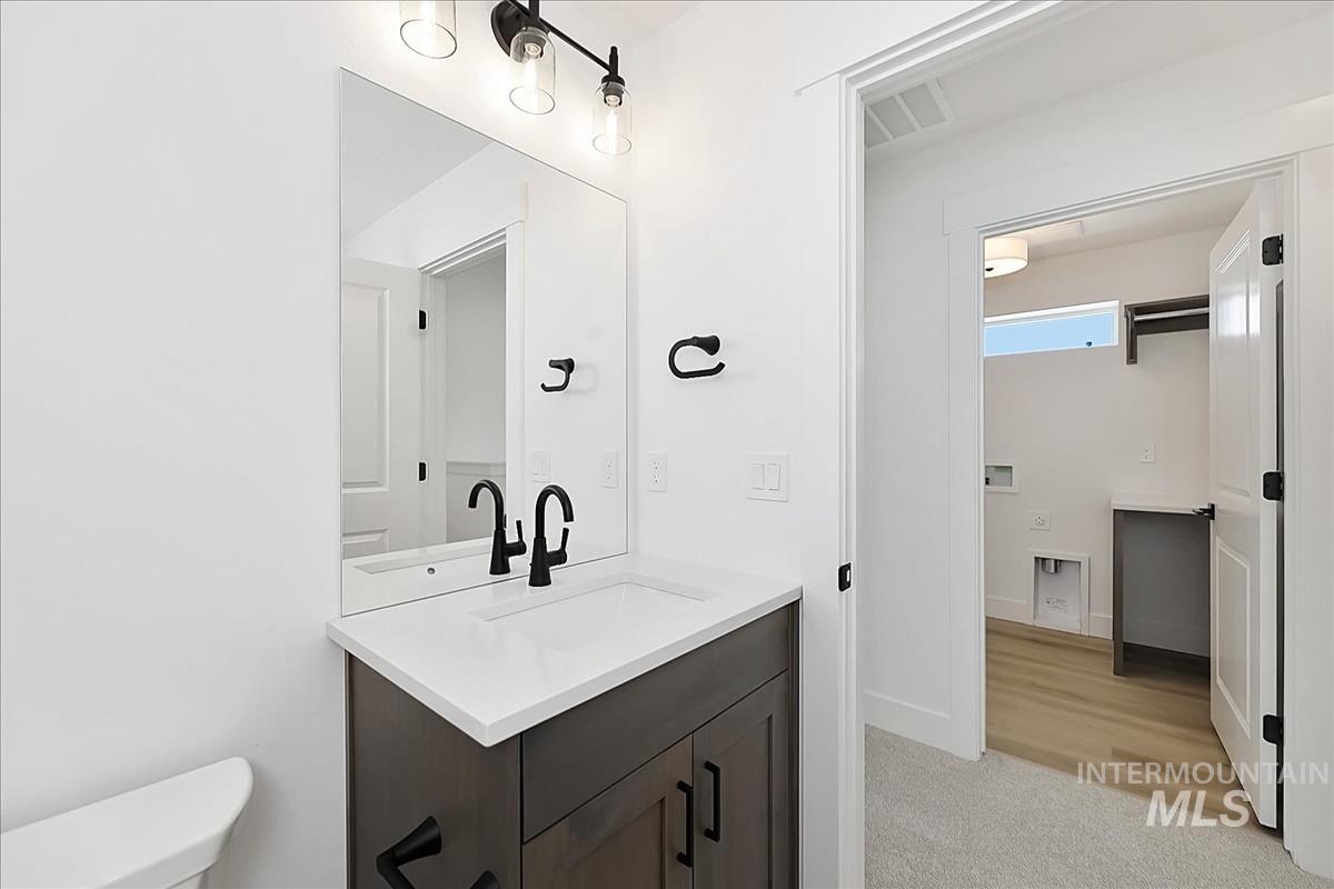 776 South Calhoun Lane Star, ID 83669 - Photo 37 of 49 Bathroom featuring a dark wood-finish vanity with a white countertop and undermount sink, complemented by matte black fixtures and a rectangular mirror