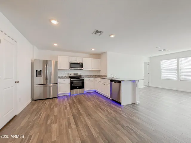 a kitchen with stainless steel appliances wooden floor and large window