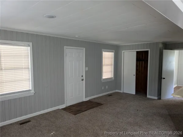 a view of an empty room with closet and a window