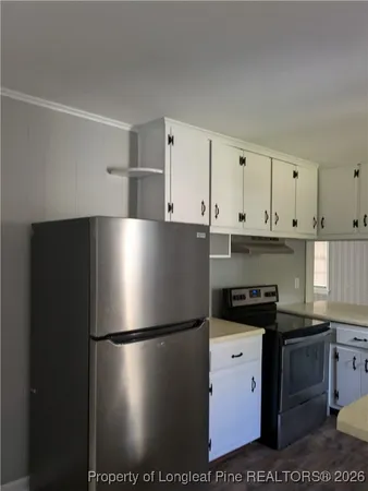 a view of a refrigerator in kitchen and white cabinets