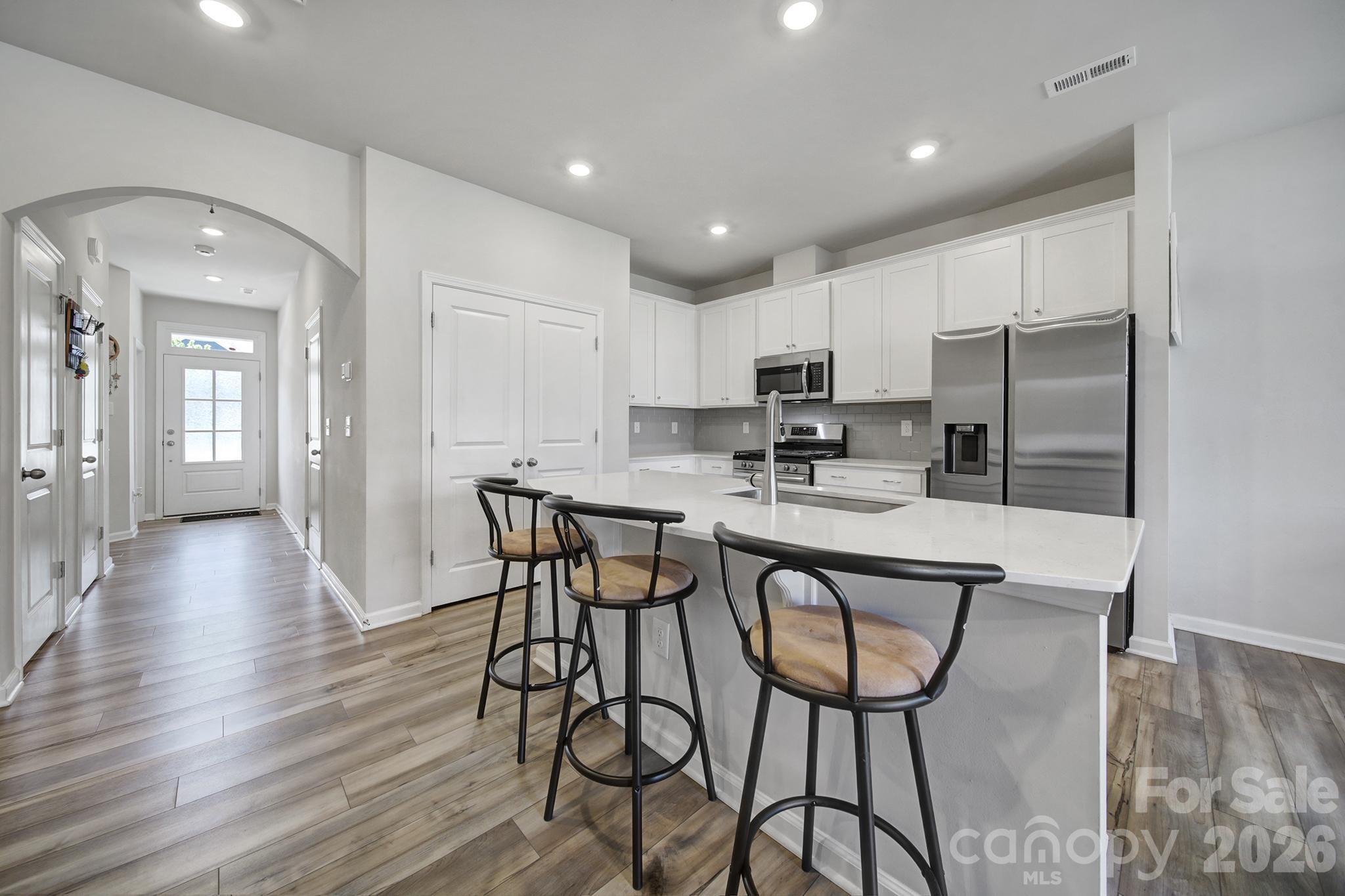 8042 Scarlet Maple Lane Fort Mill, SC 29708 - Photo 7 of 37 a kitchen with stainless steel appliances granite countertop a stove a sink a refrigerator and white cabinets with wooden floor