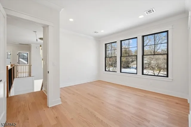 a view of an empty room with window and wooden floor