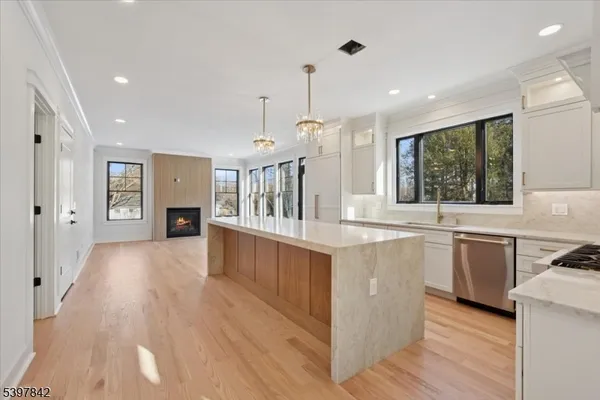 a large kitchen with granite countertop a large counter top a sink stainless steel appliances and cabinets