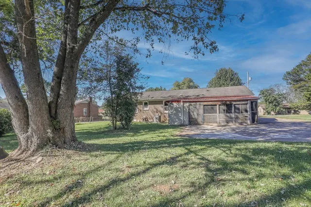 a view of a big house with a big yard and large tree