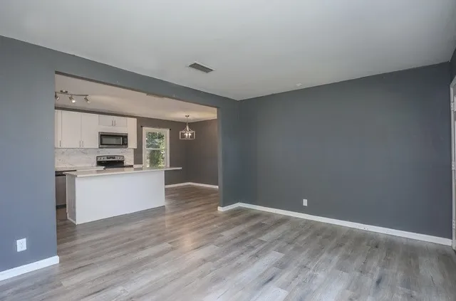 a view of kitchen with kitchen island wooden floor and stainless steel appliances