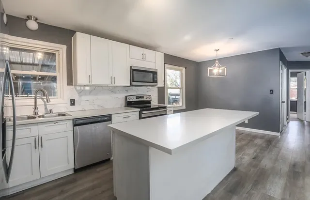 a kitchen with kitchen island a sink dishwasher a stove with wooden floor and cabinets