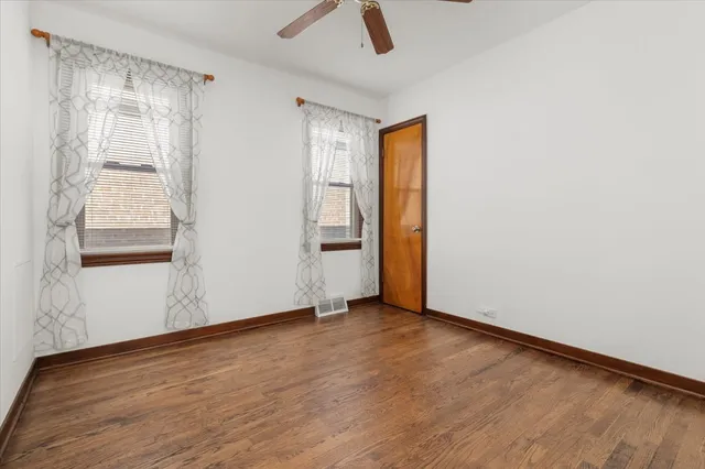 an empty room with wooden floor closet and windows