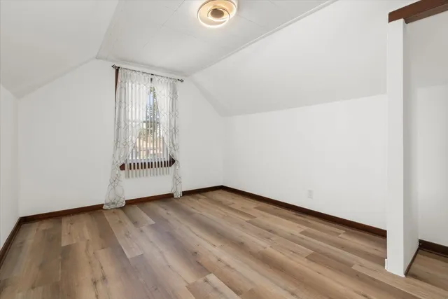 a view of an empty room with wooden floor and closet