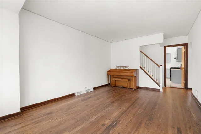 a view of an empty room with wooden floor and stairs
