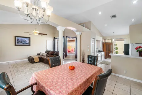 a dining room with wooden floor a chandelier a wooden table and chairs