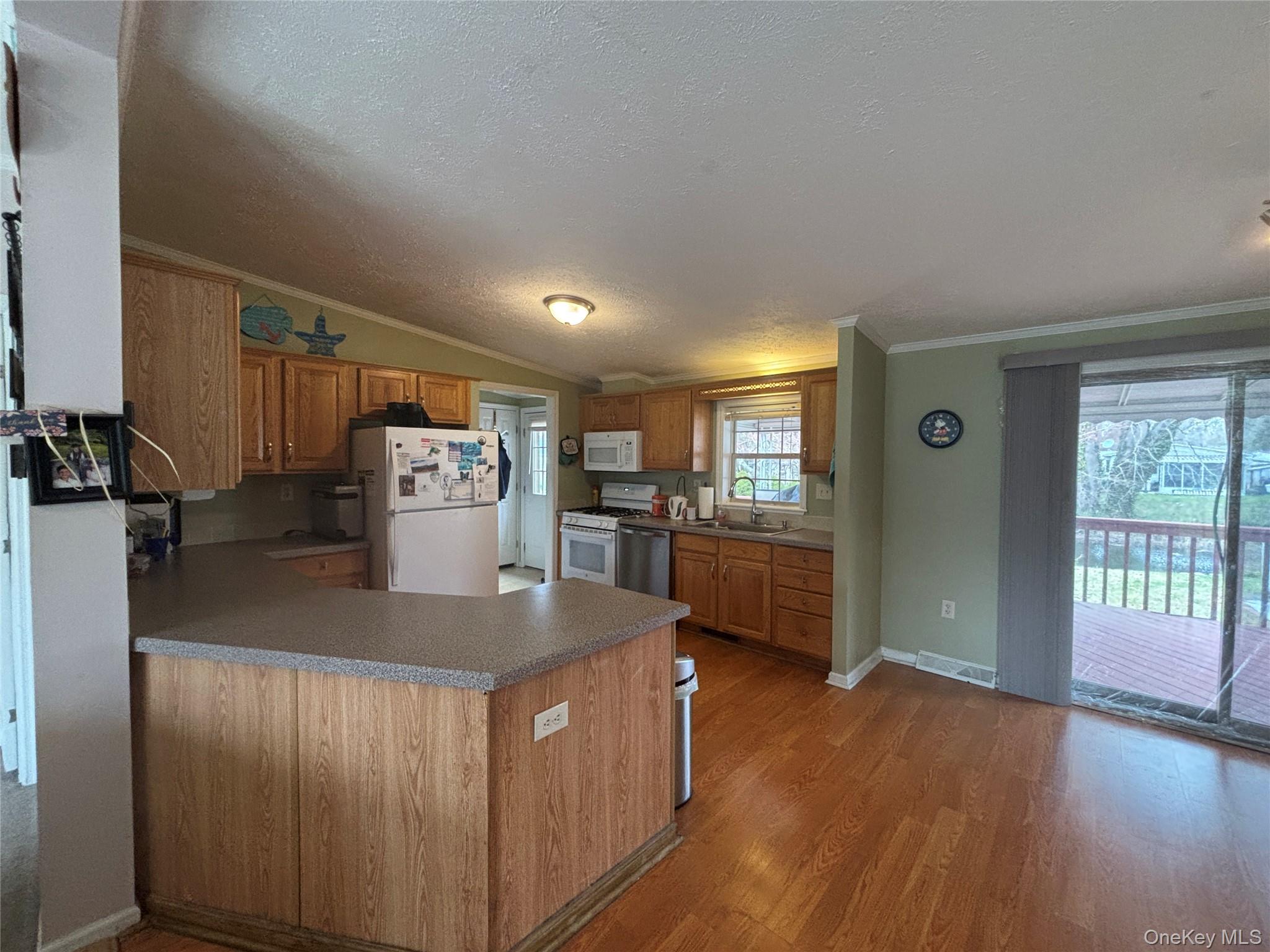 1661 Old Country Road, Unit 417 Riverhead, NY 11901 - Photo 10 of 20 a kitchen with stainless steel appliances granite countertop a refrigerator a sink dishwasher a stove and a dining table with wooden floor