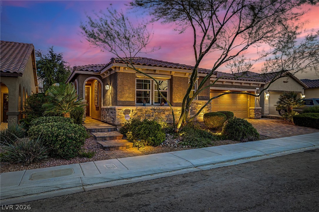7415 Campbell Ranch Avenue Las Vegas, NV 89179 - Photo 7 of 52 Illuminated by dusk, this inviting residence features a tiled roof and elegant stone accents.
