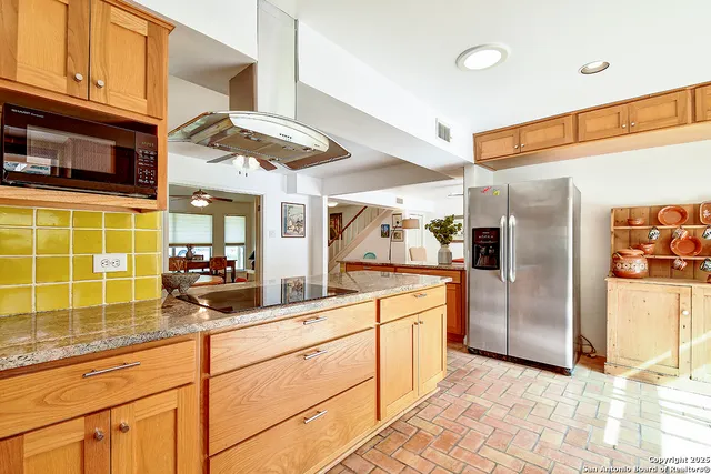 a kitchen with stainless steel appliances kitchen island granite countertop a refrigerator and a sink