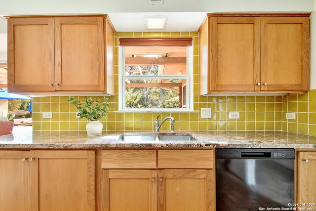 a kitchen with granite countertop a sink window and cabinets