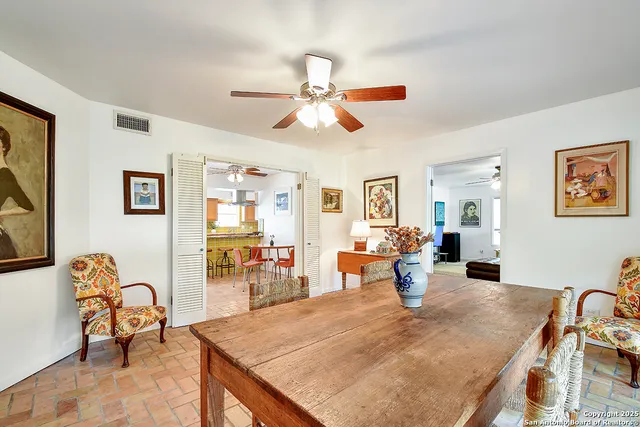 a dining room with wooden floor a chandelier fan a wooden table and chairs