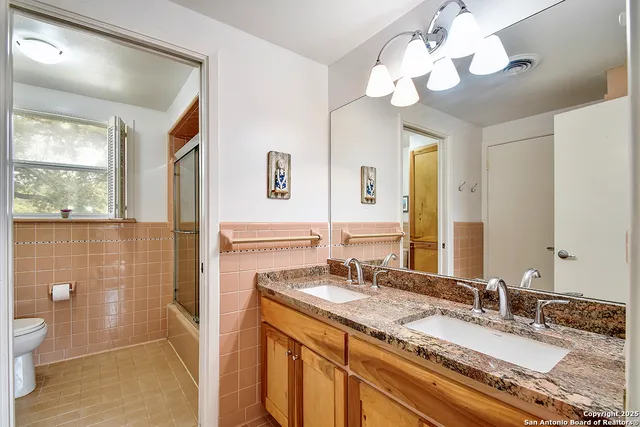 a bathroom with a granite countertop sink a toilet and a mirror