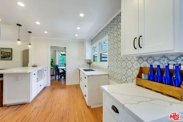 a large kitchen with stainless steel appliances a stove a sink a refrigerator and chairs