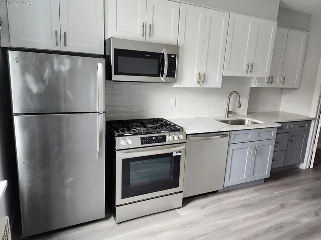 a white refrigerator freezer and a stove sitting inside of a kitchen with granite countertop stainless steel appliances