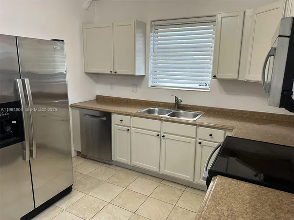 a kitchen with stainless steel appliances granite countertop a sink and a refrigerator