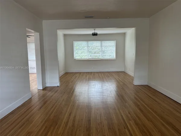 an empty room with wooden floor chandelier and windows