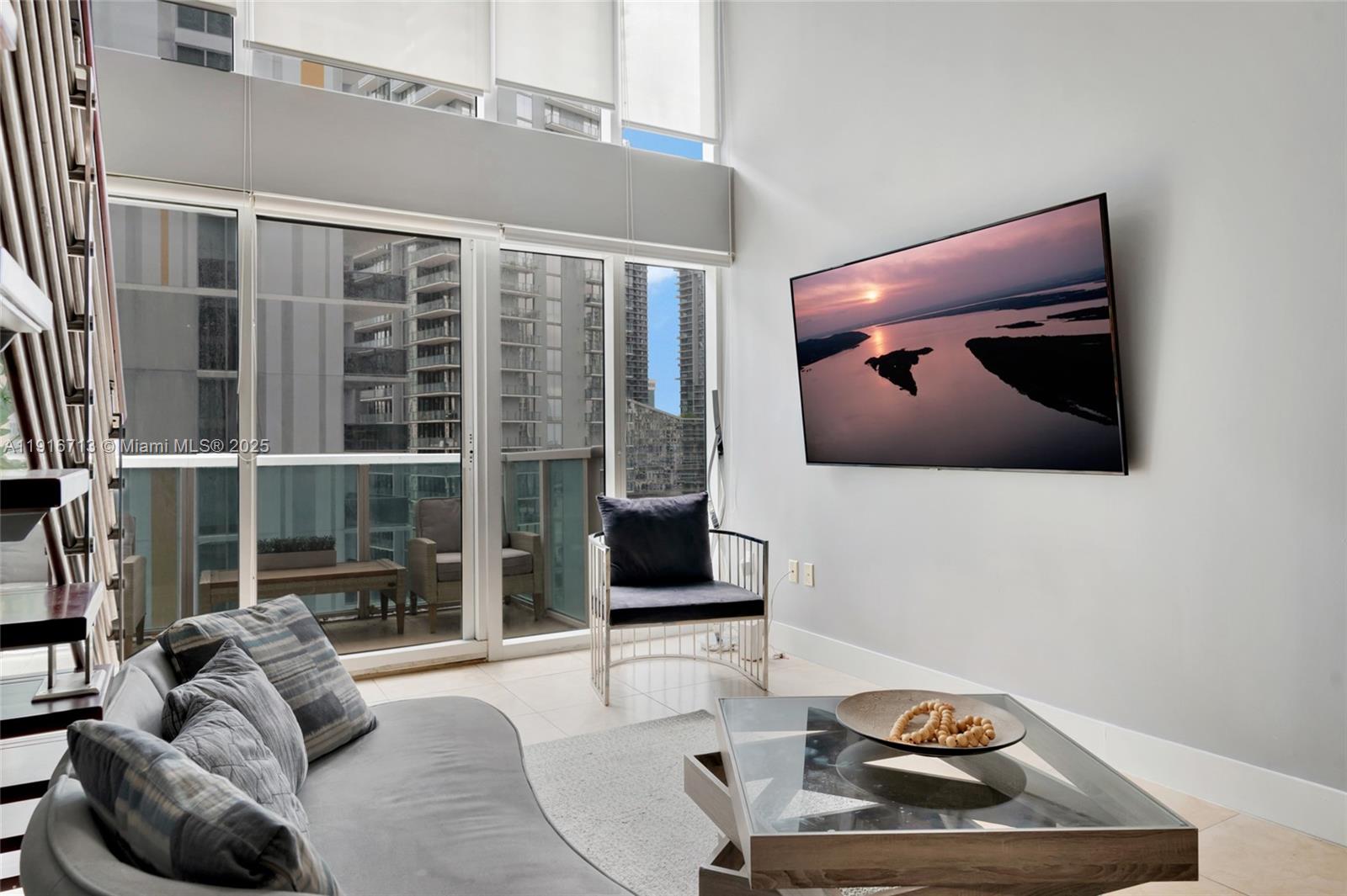 41 Southeast 5th Street, Unit 1212 Miami, FL 33131 - Photo 15 of 37 a living room with furniture and a floor to ceiling window