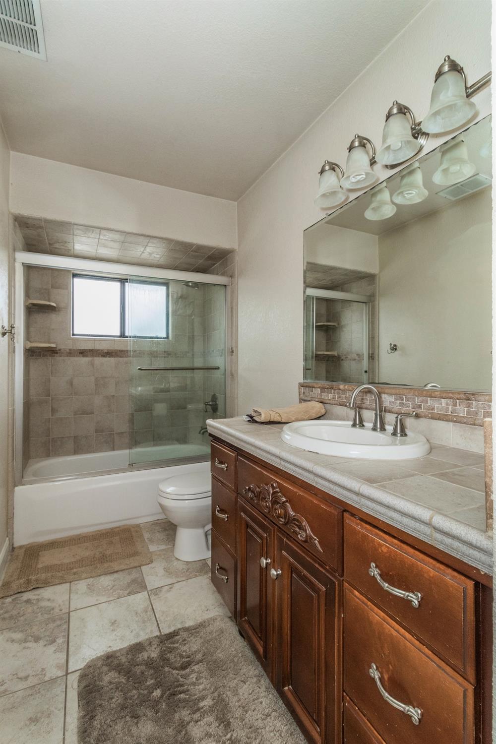 3440 Olive Street Selma, CA 93662 - Photo 15 of 21 a bathroom with a granite countertop sink a toilet and bathtub