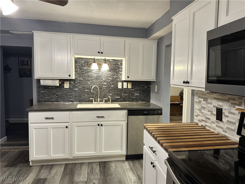 7700 Center Road Ashtabula, OH 44004 - Photo 5 of 31 Kitchen with stainless steel appliances, a sink, dark countertops, backsplash, and wood finished floors
