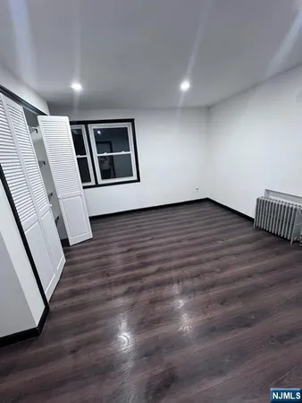 a view of an empty room with wooden floor and stairs