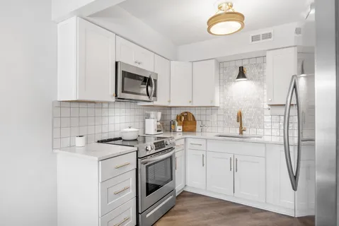 a kitchen with stainless steel appliances granite countertop a sink a stove a refrigerator and cabinets