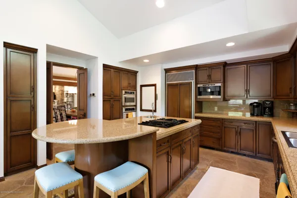 a kitchen with stainless steel appliances granite countertop a table chairs sink refrigerator and cabinets