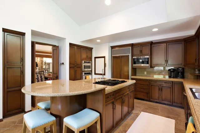 a kitchen with stainless steel appliances granite countertop a table chairs sink refrigerator and cabinets