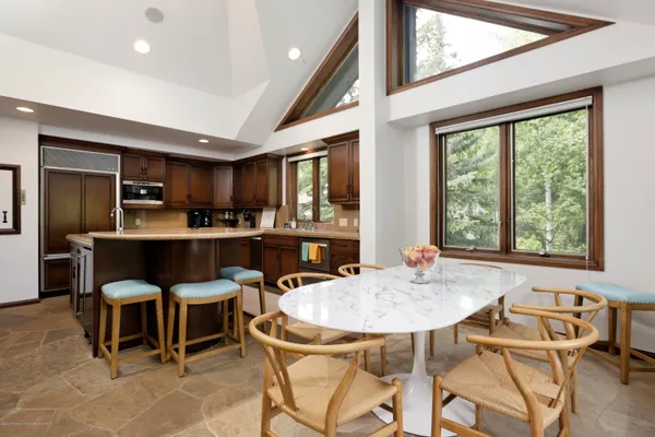 a kitchen with a dining table chairs and large windows