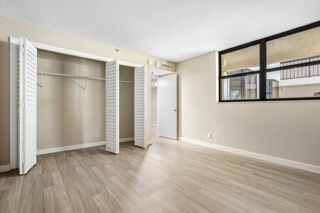 an empty room with wooden floor and windows with curtains