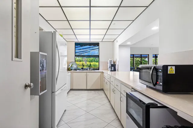 a large white kitchen with a window and refrigerator