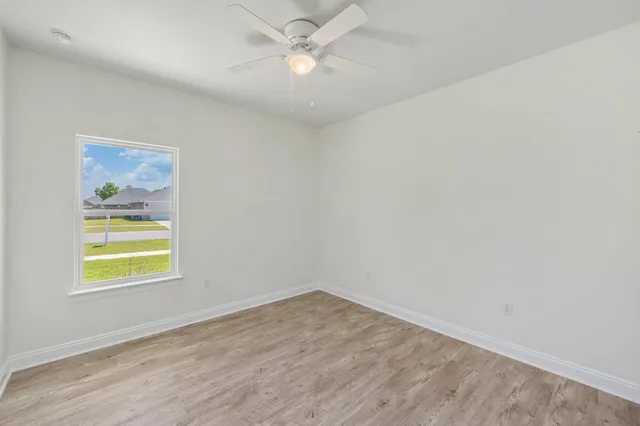 an empty room with a window and ceiling fan