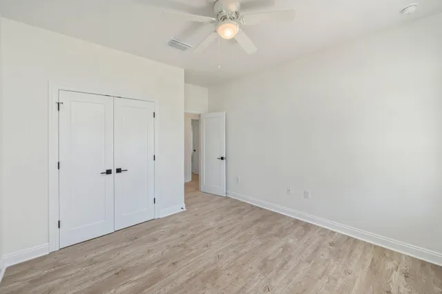 a view of an empty room with chandelier fan