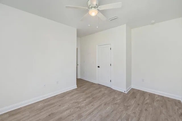 an empty room with wooden floor and fan