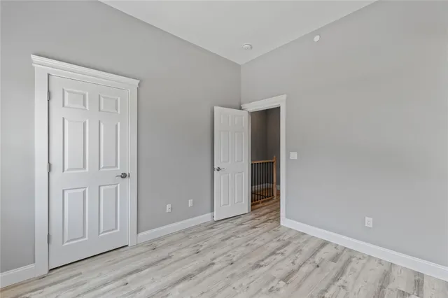 an empty room with wooden floor & closet area