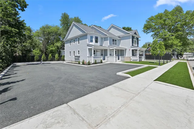 a view of a white house with a yard and potted plants