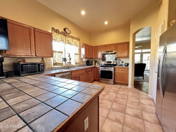 a kitchen with stainless steel appliances kitchen island granite countertop a sink counter space cabinets and a stove