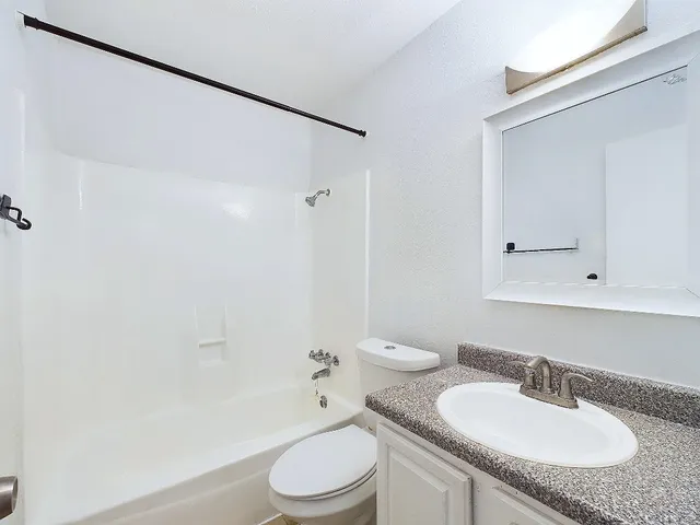 a bathroom with a granite countertop sink toilet and shower