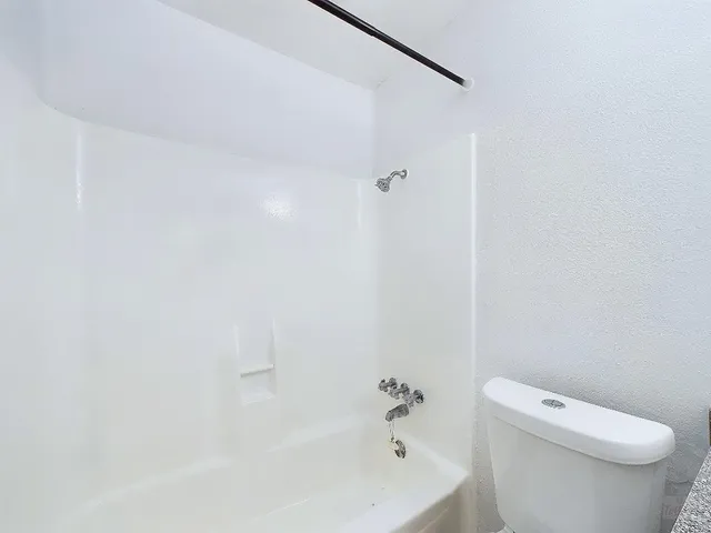 a white toilet sitting next to a bath tub