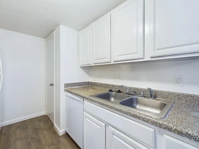 a kitchen with granite countertop white cabinets and sink