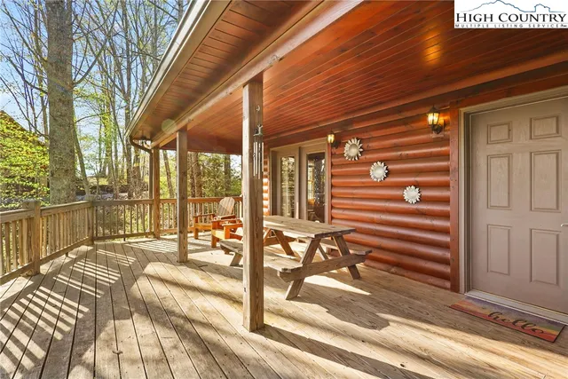 a view of a balcony with a dining table chairs and floor to ceiling window with wooden floor