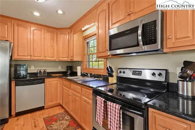 a kitchen with stainless steel appliances granite countertop a stove top oven a sink dishwasher and microwave with wooden cabinets