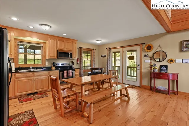 a kitchen with stainless steel appliances granite countertop a refrigerator a stove top oven and a dining table with wooden floor