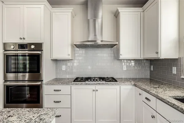 a kitchen with granite countertop white cabinets and stainless steel appliances