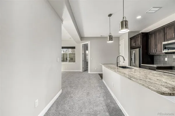 a large kitchen with kitchen island granite countertop a stove a sink dishwasher and a refrigerator with wooden floor